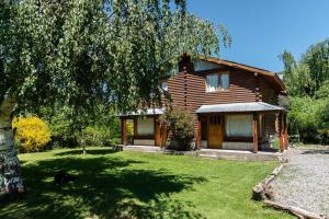 a wooden house with a yard in front of it at cabañas los Troncos in Junín de los Andes