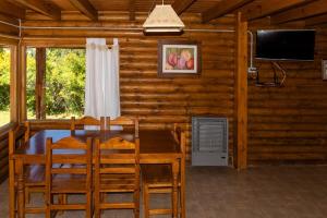 ein Esszimmer mit einem Tisch und einem TV in einer Blockhütte in der Unterkunft cabañas los Troncos in Junín de los Andes