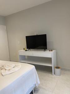 a living room with a tv on a white table at Charlotte House in Canoa Quebrada