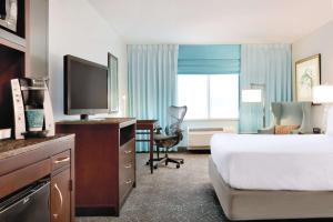 a hotel room with a bed and a desk with a television at Hilton Garden Inn Worcester in Worcester