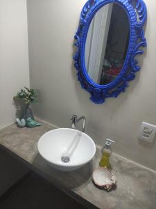 uma casa de banho com um lavatório branco e um espelho azul em Pousada Luz do Jamacá em Chapada dos Guimarães