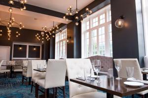 伯明翰Redmont Hotel Birmingham - Curio Collection by Hilton的有白色桌椅和窗户的餐厅