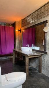 baño con 2 lavabos y aseo con cortinas moradas en Taino Beach Lofts en El Valle