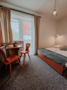 扎科帕內的住宿－Stan Relaksu - noclegi w Zakopanem，一间卧室配有一张床、一张桌子、一张床和一把椅子