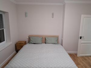 a bed in a bedroom with a white wall at Apartament la casa in Bistriţa