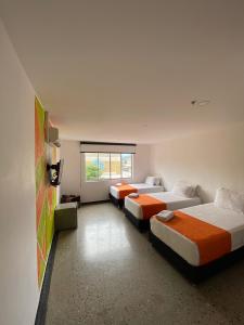 HOTEL RIVERA CENTRAL في بوكارامانغا: غرفة بثلاث اسرة ونافذة