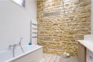 e bagno con parete in pietra e vasca. di L'escale romantique -Métro Hôtel de Ville a Lione