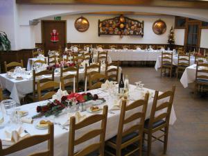 uma sala de jantar com mesas e cadeiras com toalhas de mesa brancas em Albergo Esposito em Barzio