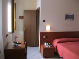 um quarto de hotel com uma cama vermelha e uma mesa em Albergo Esposito em Barzio