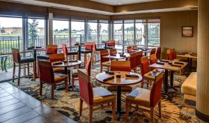 un restaurante con mesas, sillas y ventanas en DoubleTree by Hilton West Fargo Sanford Medical Center Area en Fargo