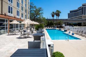 a swimming pool with tables and chairs next to a building at DoubleTree by Hilton Biloxi in Biloxi