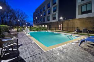 a swimming pool with chairs and a building at Hampton Inn Pleasant View in Pleasant View