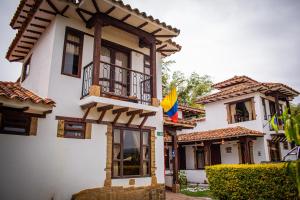 Casa blanca con balcón y banderas. en El Pozzo Hotel Campestre, en Villa de Leyva