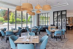 un restaurante con mesas, sillas y ventanas grandes en Hilton Garden Inn Boston Brookline, Ma en Brookline