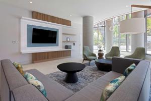 sala de estar con sofá y TV en Hilton Garden Inn Boston Brookline, Ma, en Brookline