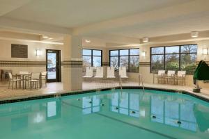 a pool in a hotel with tables and chairs at Hampton Inn Boston/Braintree in Braintree