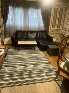 a living room with a black leather couch and a rug at Cozy Nice Apartment Room Free Wi-Fi an parking in Asnières-sur-Seine