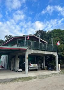 ein vor einem Gebäude mit Balkon geparktes Auto in der Unterkunft MOOZ LODGE, the local discovery in Afareaitu