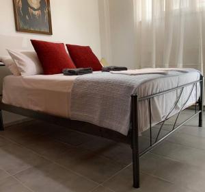Central Apartment near metro Keramikos- Airport في أثينا: سرير مع وسائد حمراء وبيضاء في غرفة النوم