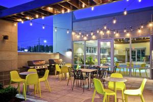 eine Terrasse mit Tischen, Stühlen und einem Grill in der Unterkunft Home2 Suites By Hilton Walpole Foxborough in Foxborough