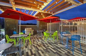 un patio con mesas, sillas y sombrillas rojas en Home2 Suites By Hilton Beaumont, Tx, en Beaumont