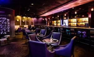 内蒂克The Verve Boston Natick, Tapestry Collection by Hilton的一间设有紫色椅子的餐厅和一间酒吧
