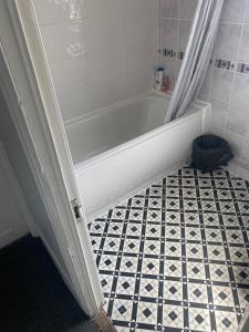 uma casa de banho com banheira e piso em azulejo preto e branco em bnb em Belfast