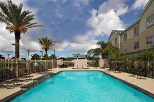 a pool with chairs and palm trees and a building at Hilton Garden Inn Beaumont in Beaumont