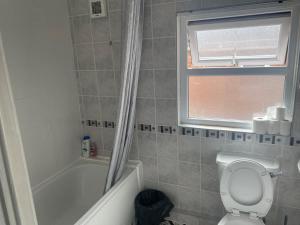 baño con aseo, bañera y ventana en bnb, en Belfast