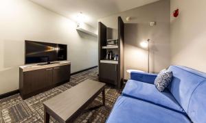 a living room with a blue couch and a tv at Hilton Garden Inn Beaumont in Beaumont