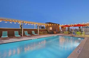 ein Pool mit Stühlen und Sonnenschirmen in der Nacht in der Unterkunft Home2 Suites By Hilton Port Arthur in Port Arthur