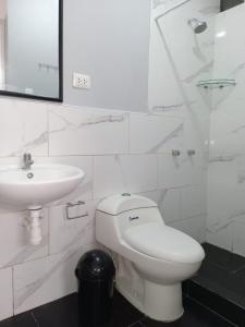 La salle de bains blanche est pourvue de toilettes et d'un lavabo. dans l'établissement La casa de Maria- Playa Huanchaquito, à Huanchaquito