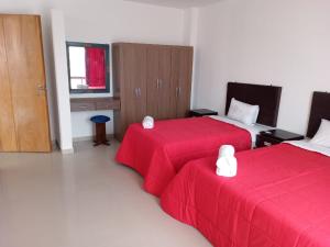 Habitación de hotel con 2 camas con sábanas rojas en La casa de Maria- Playa Huanchaquito, en Huanchaquito