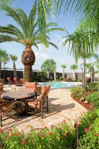 un patio con una mesa, sillas y una palmera en Hampton Inn I-10 & College Drive en Baton Rouge