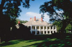 uma grande casa branca com um alpendre num relvado em Embassy Suites Baton Rouge em Baton Rouge