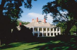 a large white house with a porch on a lawn at Embassy Suites Baton Rouge in Baton Rouge