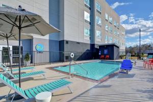 a pool with chairs and an umbrella next to a building at Tru By Hilton Baton Rouge Citiplace in Baton Rouge