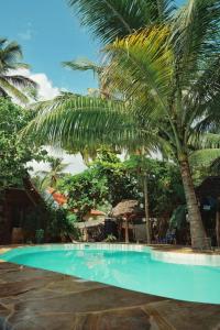 a blue swimming pool with palm trees in the background at Ocean Boho House in Jambiani