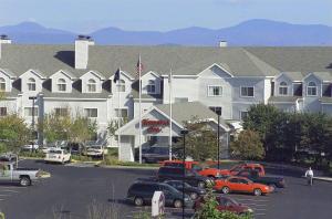 Un gran edificio blanco con coches aparcados en un estacionamiento. en Hampton Inn Burlington - Colchester, en Burlington