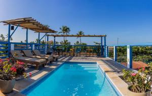 a swimming pool with a patio and a table and chairs at Vila Maria Pousada in Jericoacoara