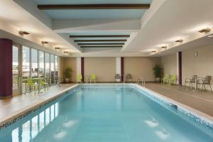 a pool in a hotel room with chairs and tables at Home2 Suites By Hilton Williamsville Buffalo Airport in Williamsville