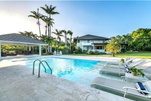 a swimming pool with chairs and a house at Sunny Vacation Villa No 83 in San Rafael del Yuma