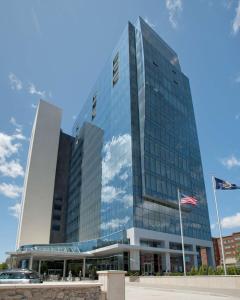 Um edifício alto com uma bandeira americana à frente. em Embassy Suites Buffalo em Buffalo