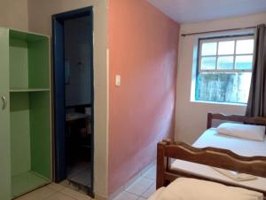 a room with two beds and a window and a mirror at Hospedaria Mineira Hostel Pousada in Ouro Preto