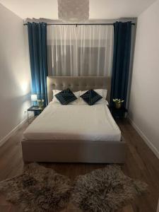 a bedroom with a bed with blue curtains and two rugs at Apartament 3 camere in Baia Mare