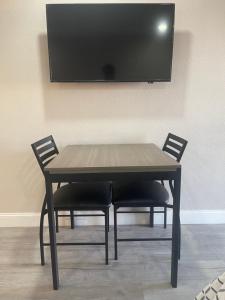 a wooden table with two chairs and a television on a wall at Town House Motel in Sanger