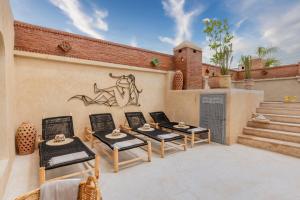 une terrasse avec quatre chaises et un mur orné d'une fresque murale. dans l'établissement Riad Celema & Spa, à Marrakech