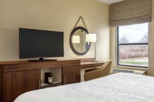 Habitación de hotel con cama, TV y espejo. en Hampton Inn Akron-Fairlawn, en Montrose