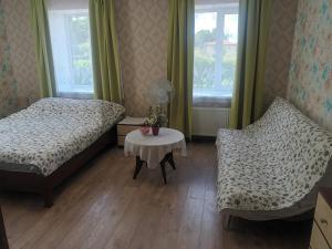 a bedroom with two beds and a table and a chair at Dzīvoklis Tukuma centrā in Tukums
