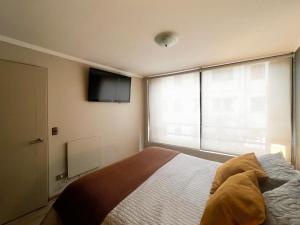 a bedroom with a bed and a tv on the wall at Depto CostaneraCenter in Santiago